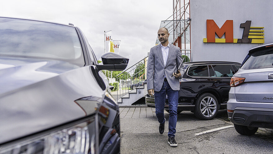 Ein Mann geht über einen Parkplatz mit drei Autos