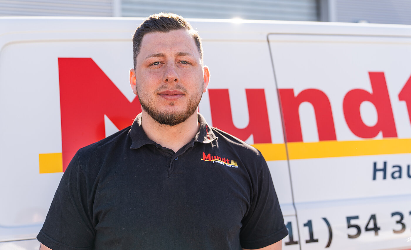 Ein lächelnder Mann steht vor einem Transporter