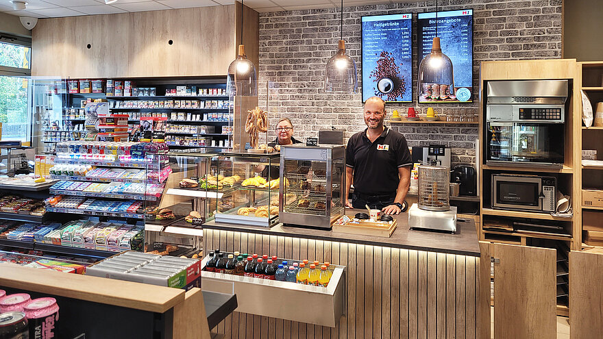 Ein Mann und eine Frau stehen an einer Kasse mit verschiedenen Konsumgütern