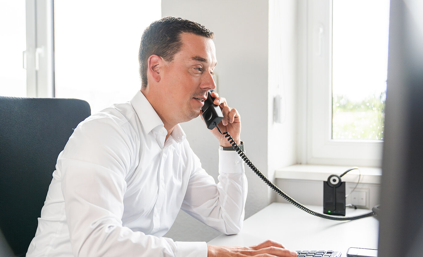 Ein telefonierender Mann vor einem Computer