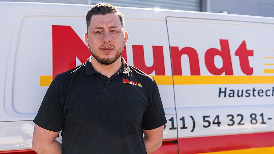 Ein lächelnder Mann steht vor einem Transporter